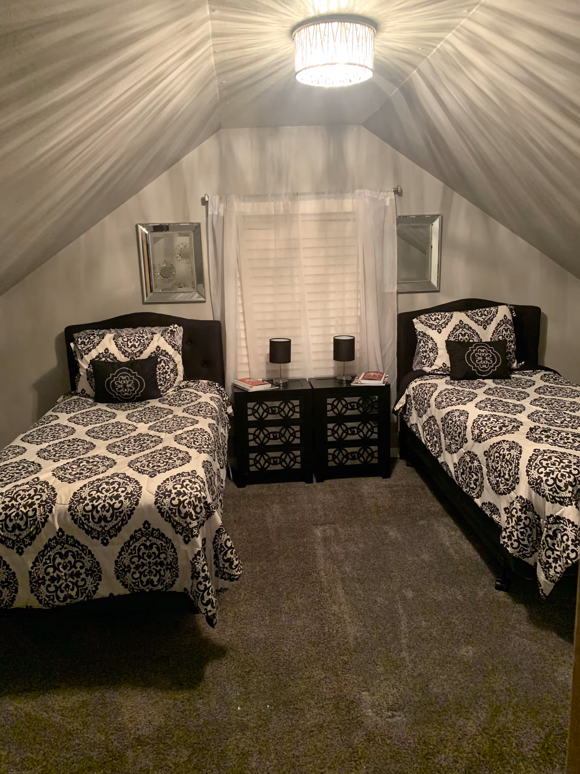 Two twin beds with black-and-white damask bedding in a small attic bedroom.