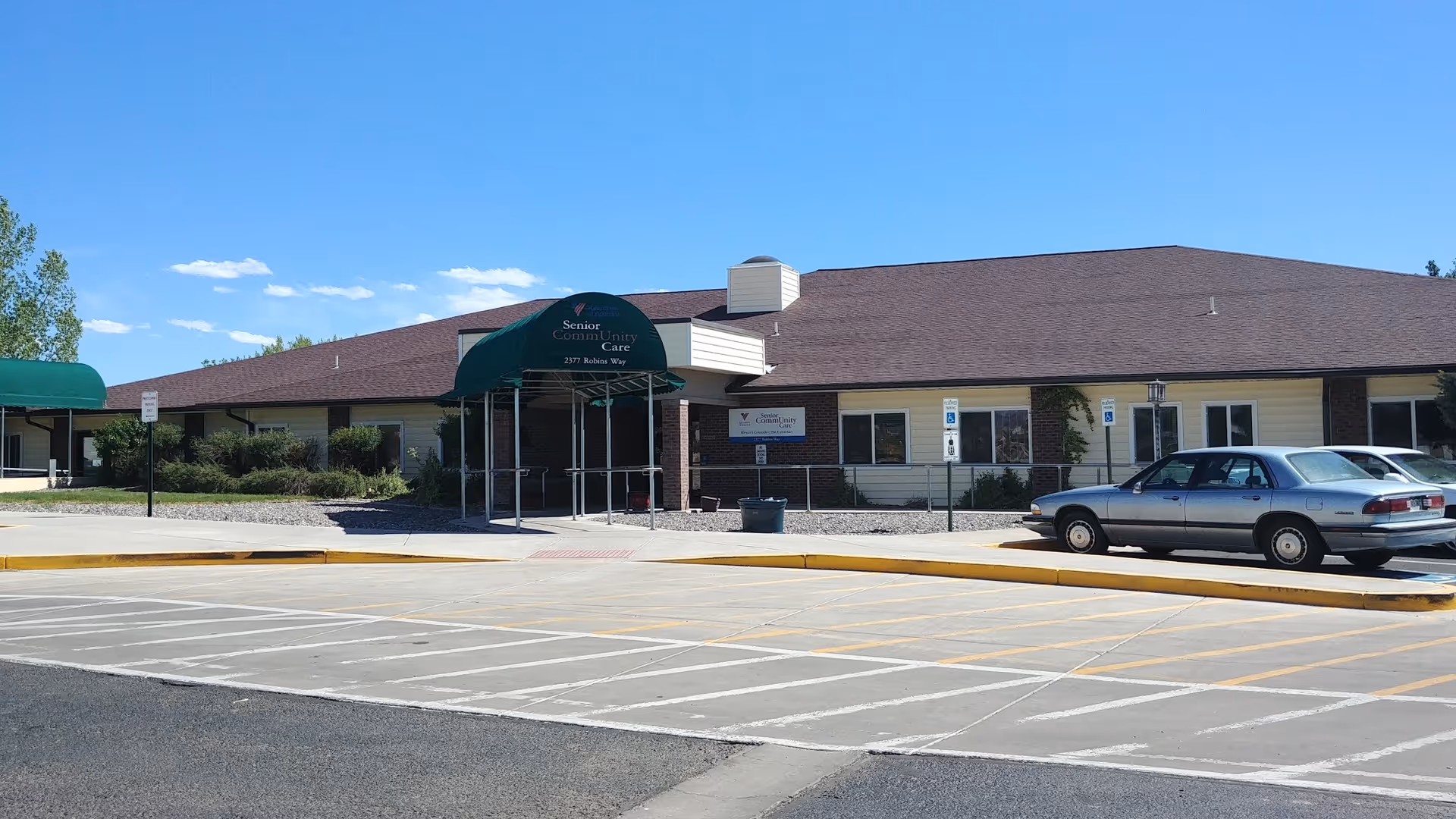Single-story senior care facility with green entrance awning and a parked car.