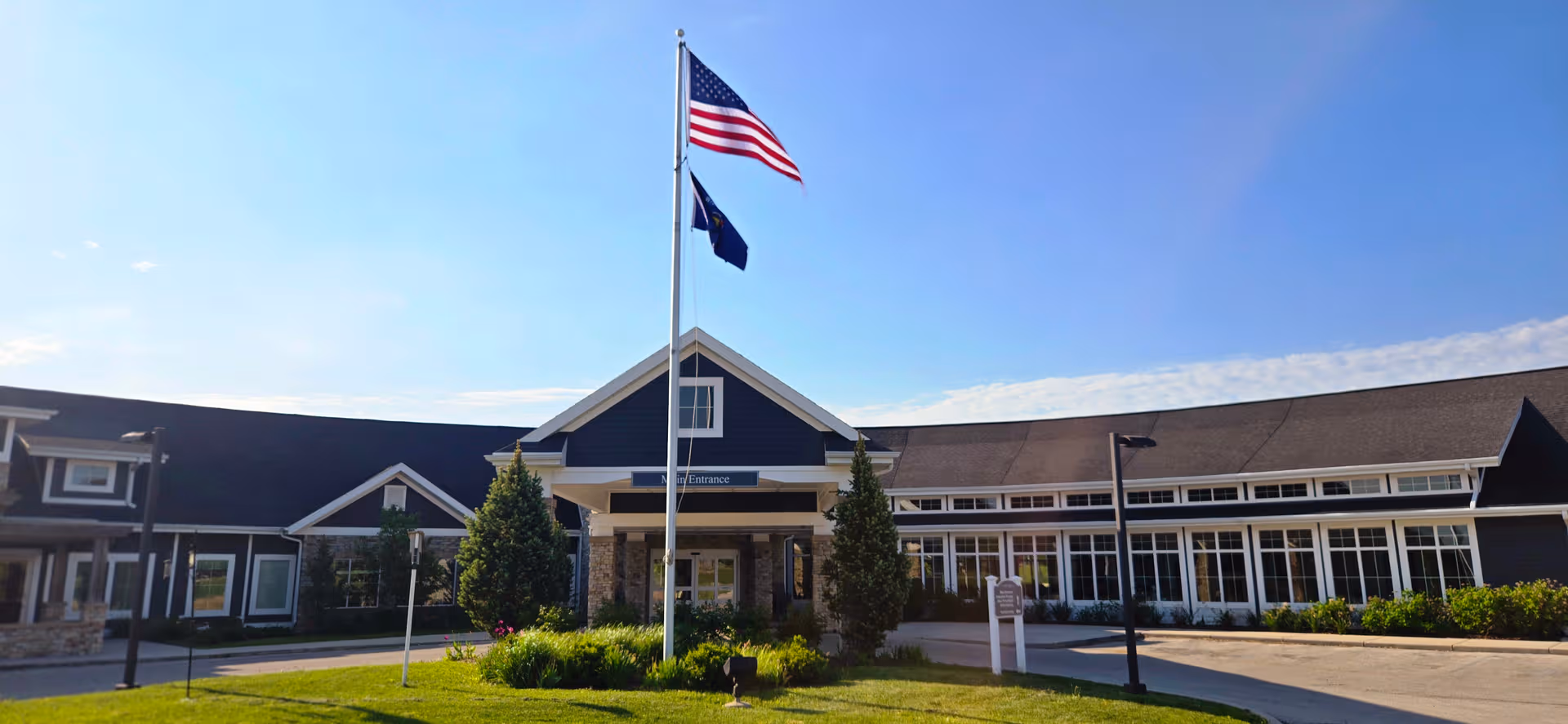 Exterior view of a senior living community building with flagpole and entrance.