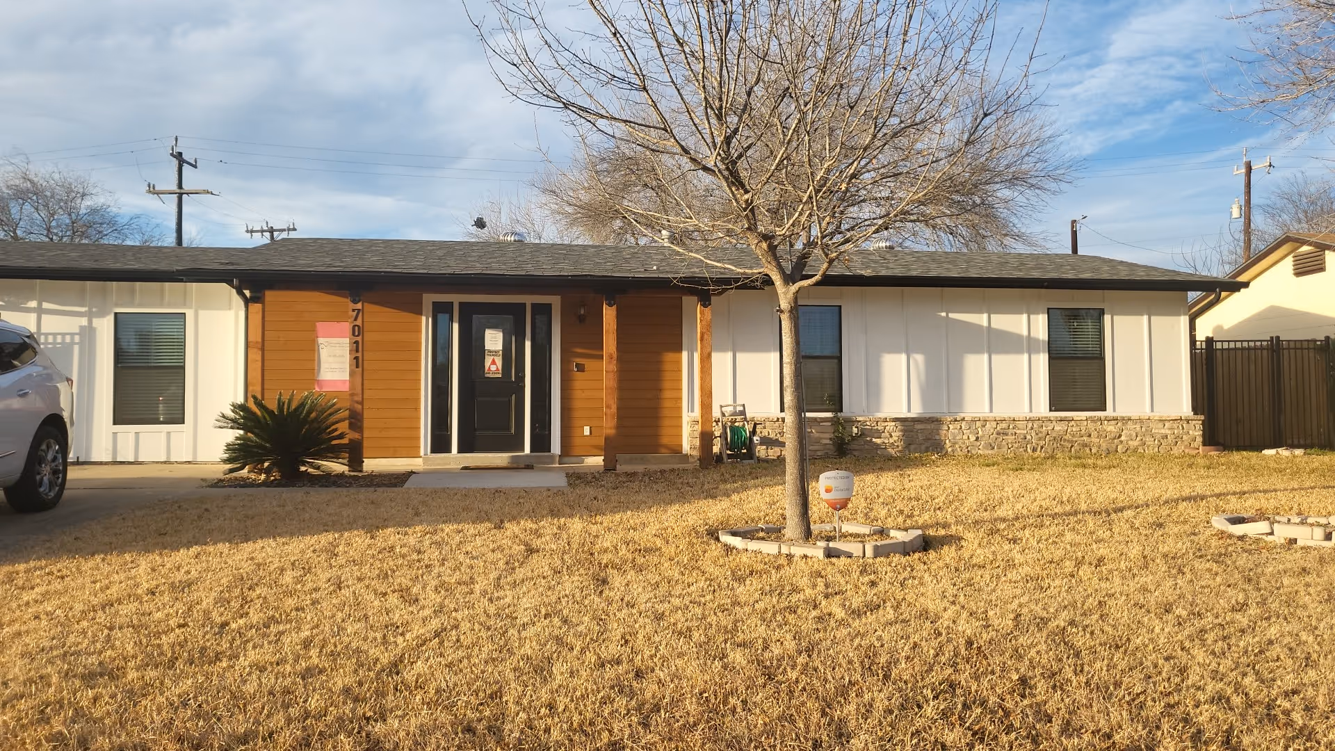 Front exterior of a single-story care facility with a tree and grassy yard.