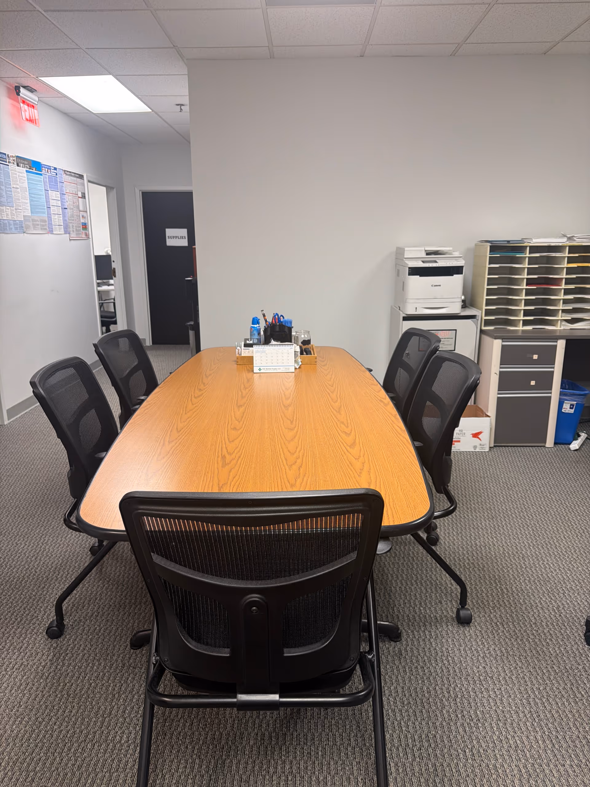 Long wooden conference table with black chairs in an office-style meeting room.