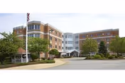 Exterior view of Oakland Grove Health Care Center with driveway, trees, and central entrance.