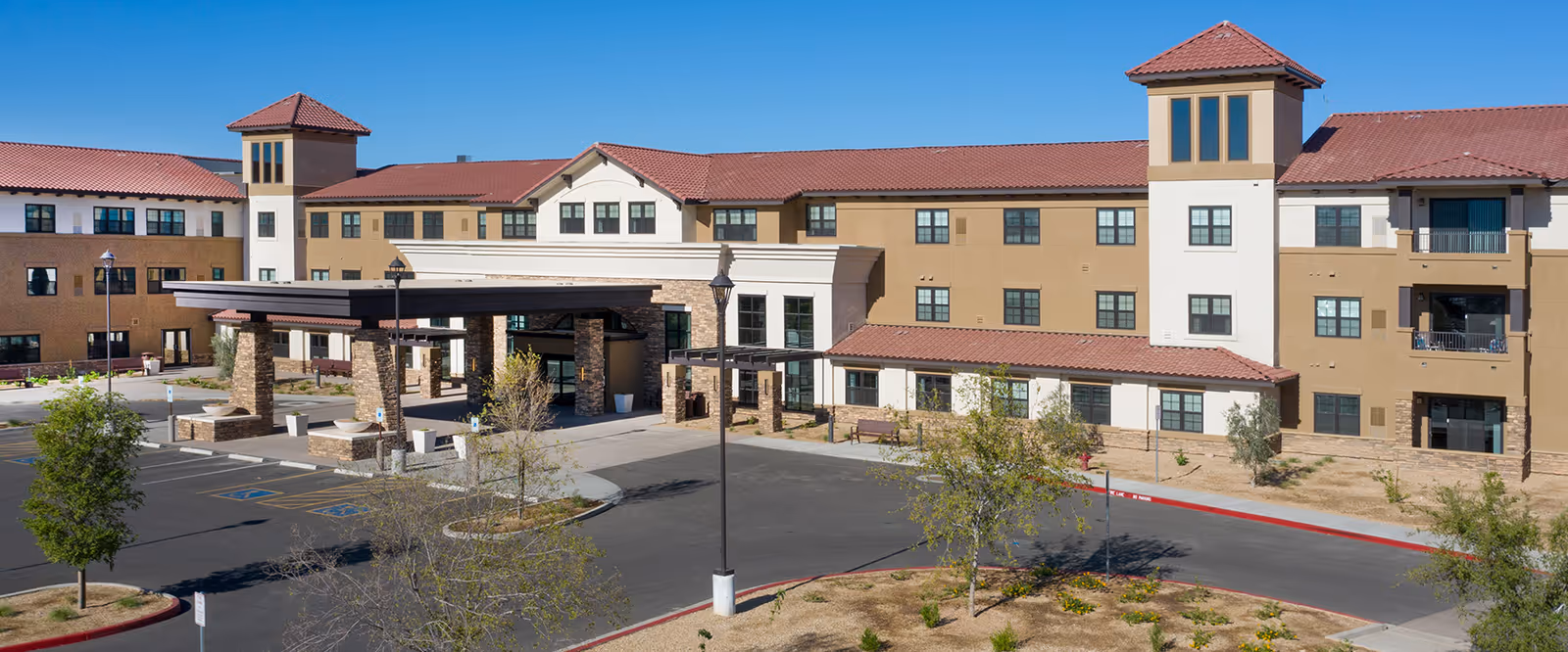 Exterior view of Clarendale of Chandler, a multi-story beige senior residence with a porte-cochère.