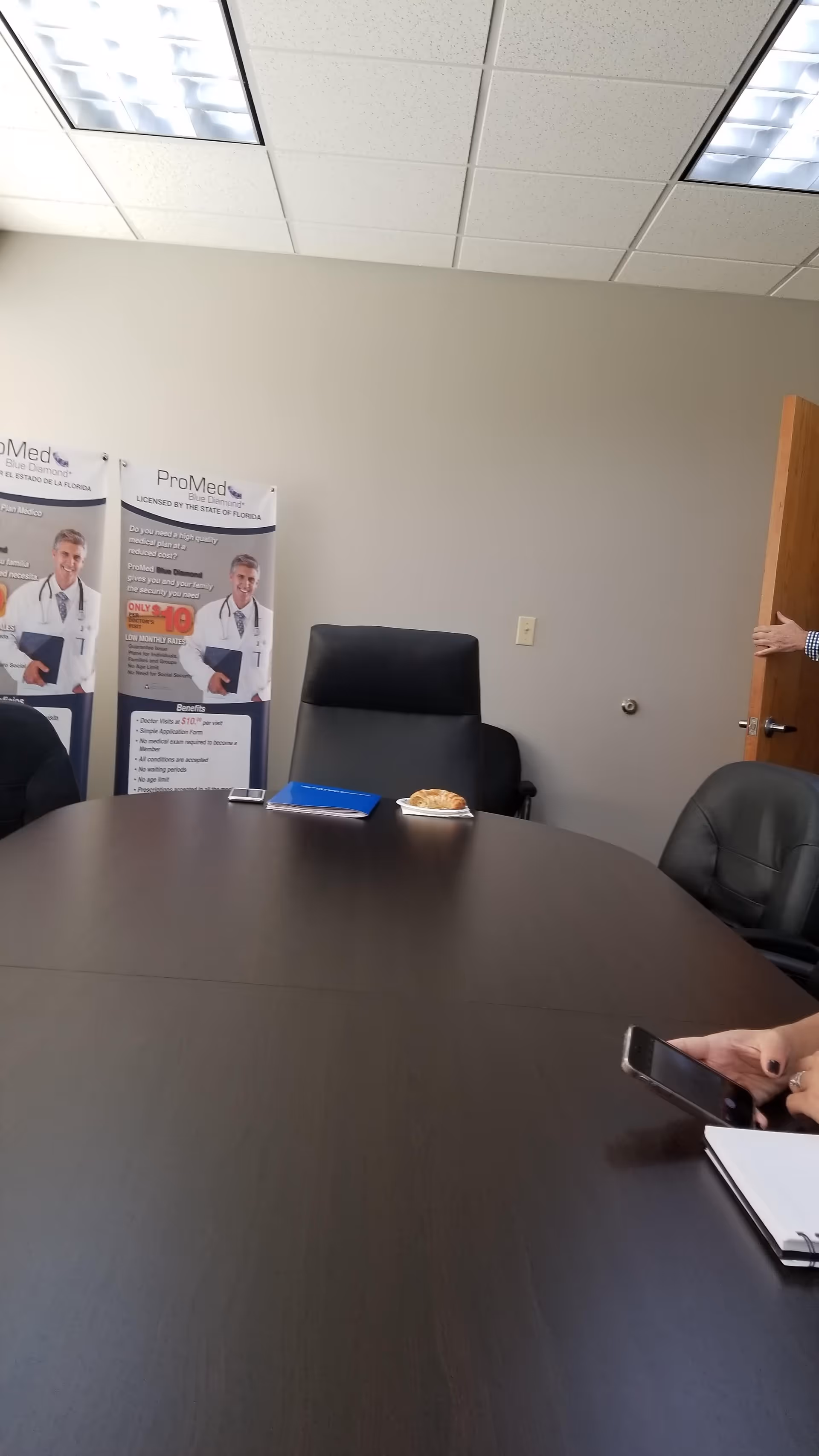A large dark conference table in a medical office meeting room with posters.