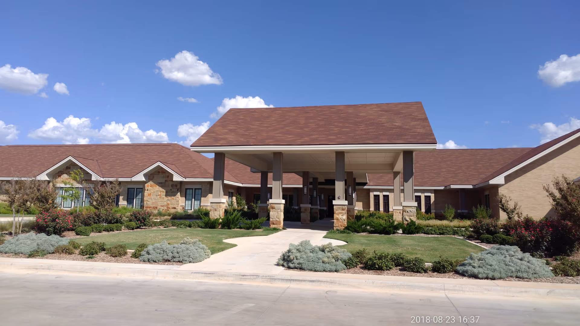 Exterior view of a hospice care facility with a large entrance canopy and landscaped grounds.