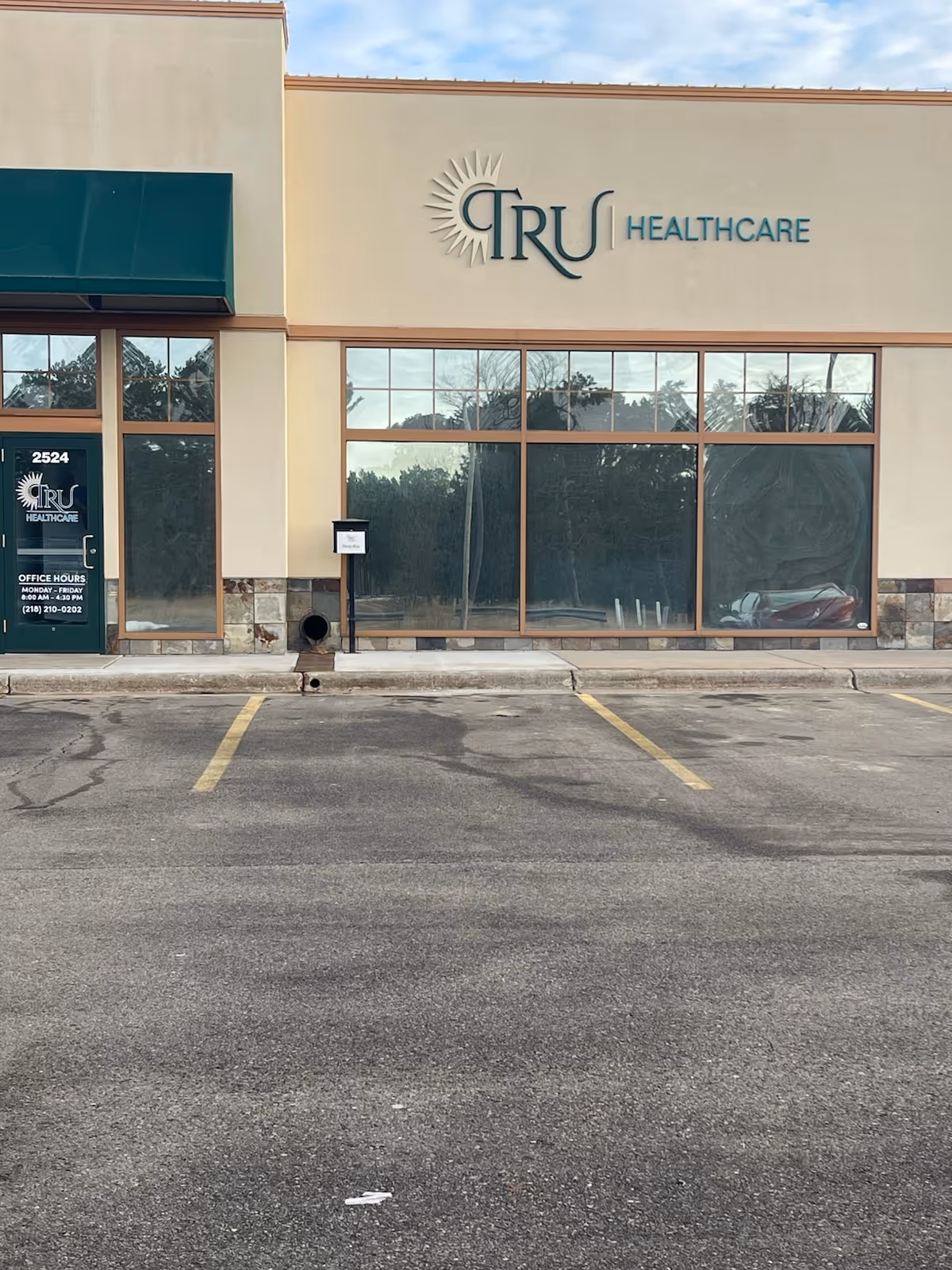 Facade of a TRU Healthcare building with large windows and a parking lot.