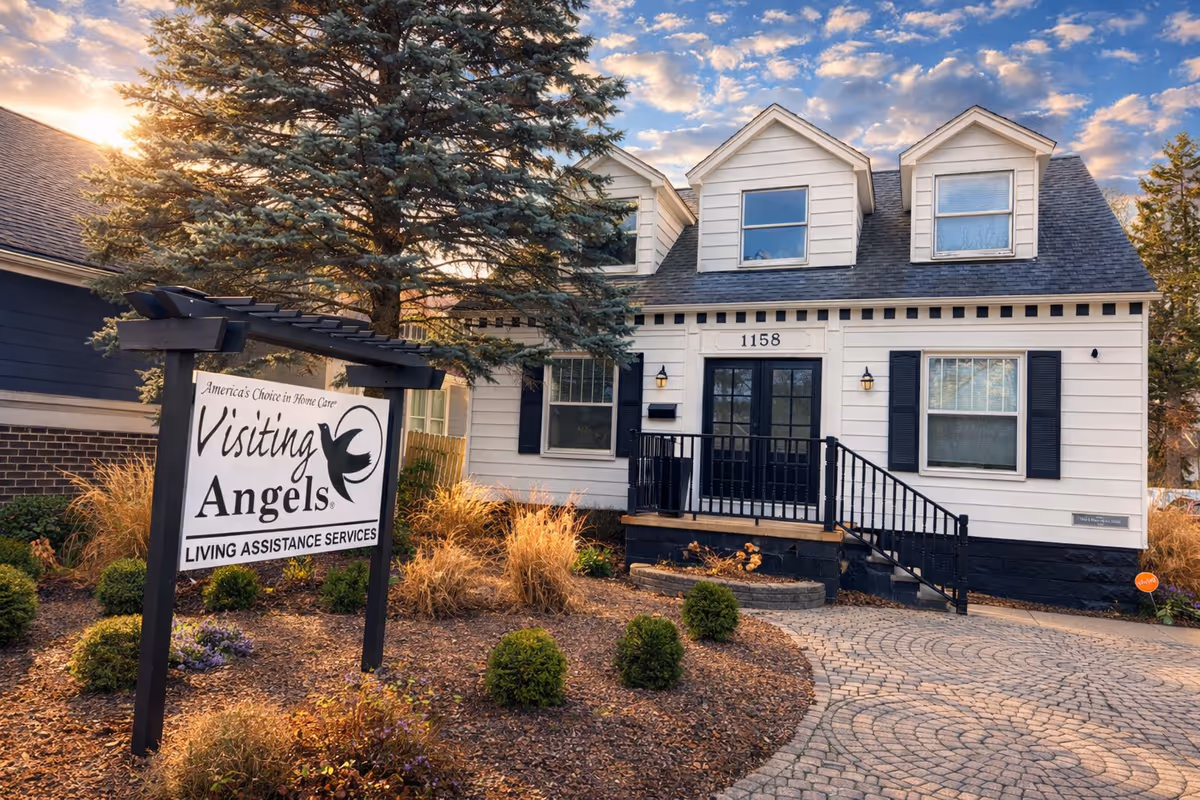 Exterior view of a white senior care facility with a front entrance and Visiting Angels sign.