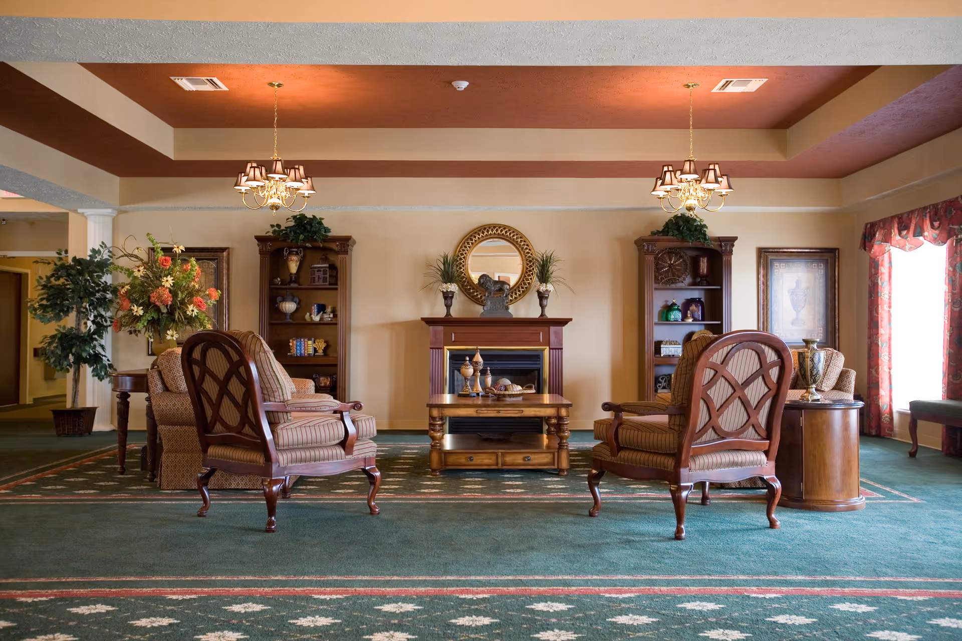 A spacious lounge in a senior living facility with chairs and fireplace.