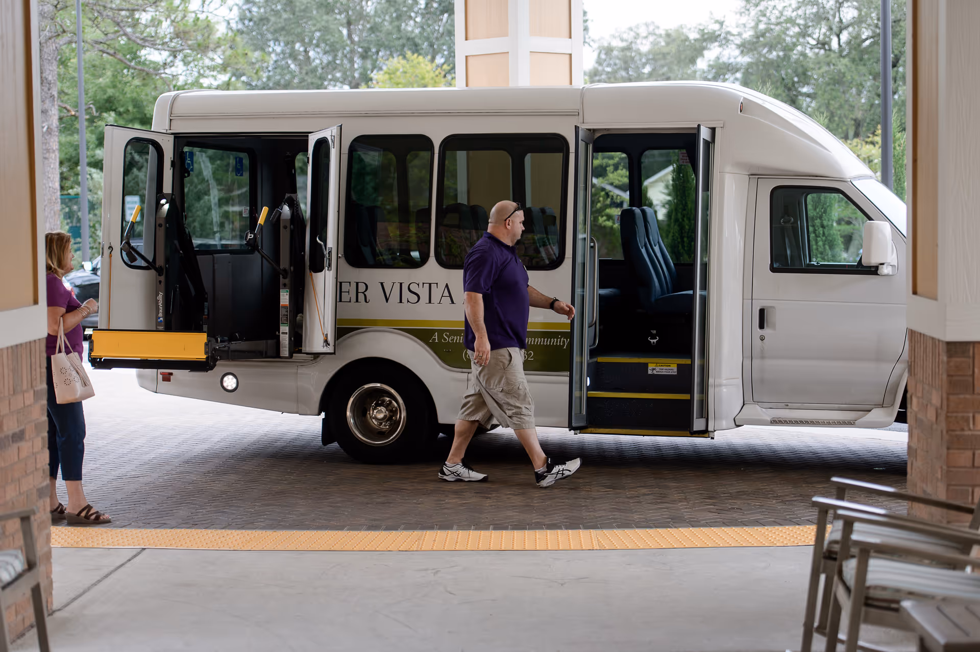 Shuttle bus at the Summer Vista Assisted Living entrance with a person.