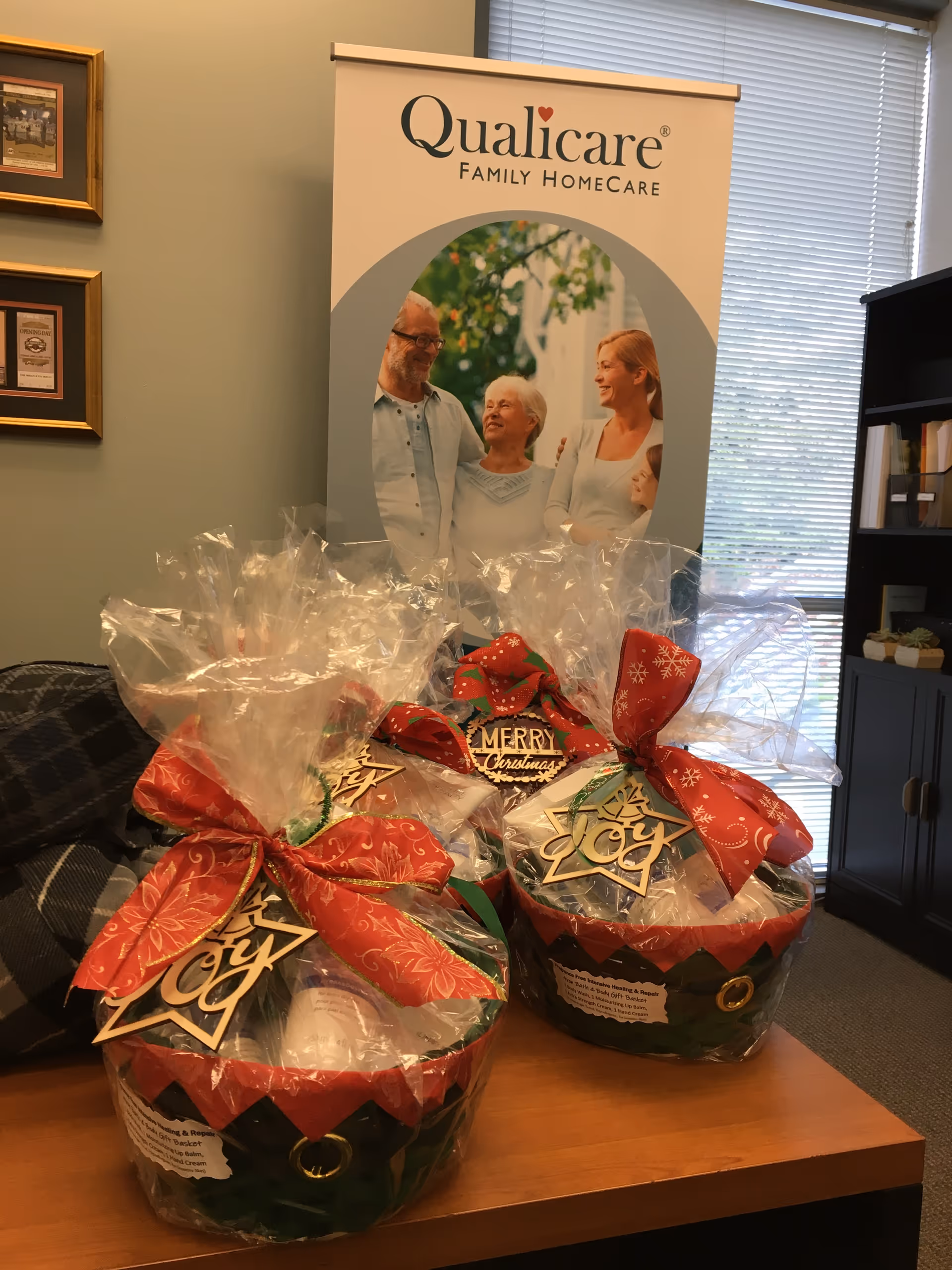 Interior reception area with a Qualicare banner and wrapped Christmas gift baskets on a table.