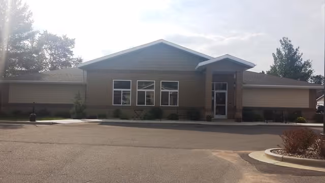 Front view of a single-story brick senior living facility with parking.
