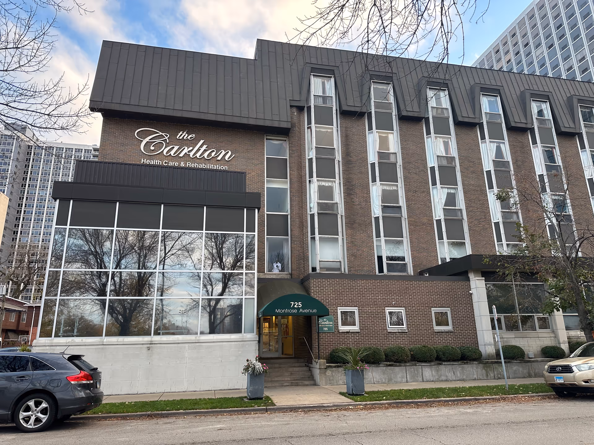 Exterior front of The Carlton health care and rehabilitation building showing its sign, rows of windows, and the entrance awning.