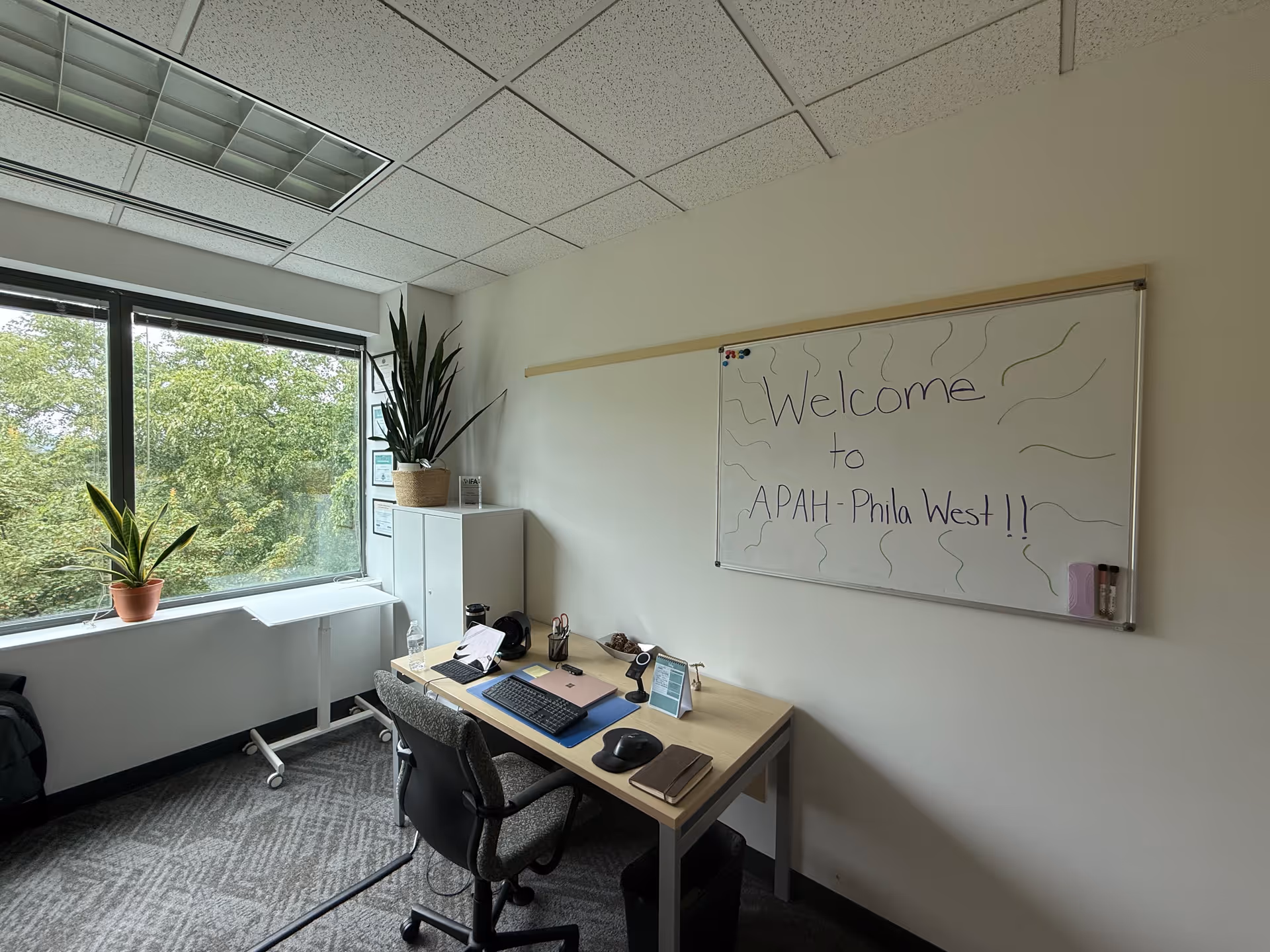 Office space inside a senior living facility with a desk, computer, and welcome board.