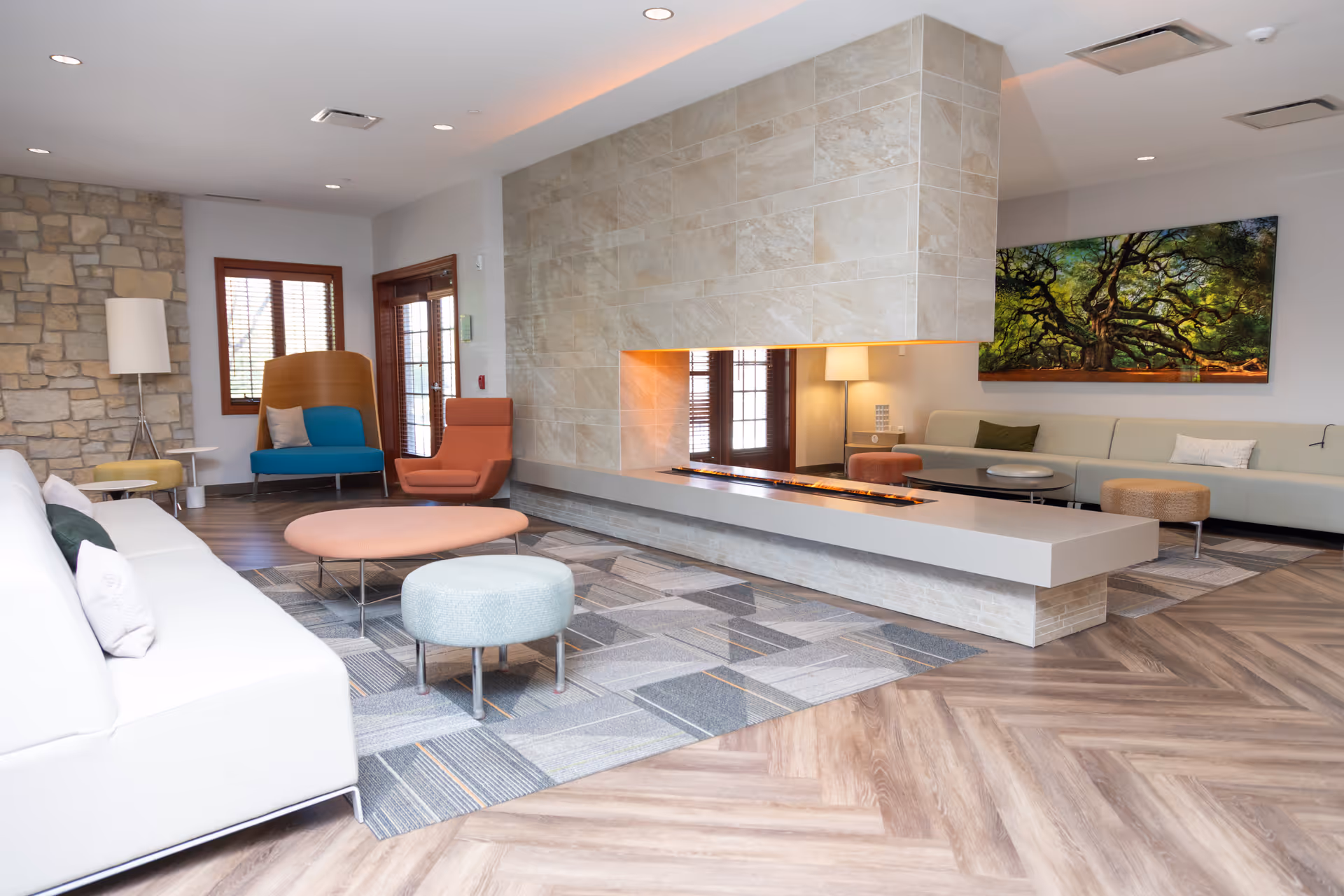 Senior living facility lounge with modern seating and a central fireplace.