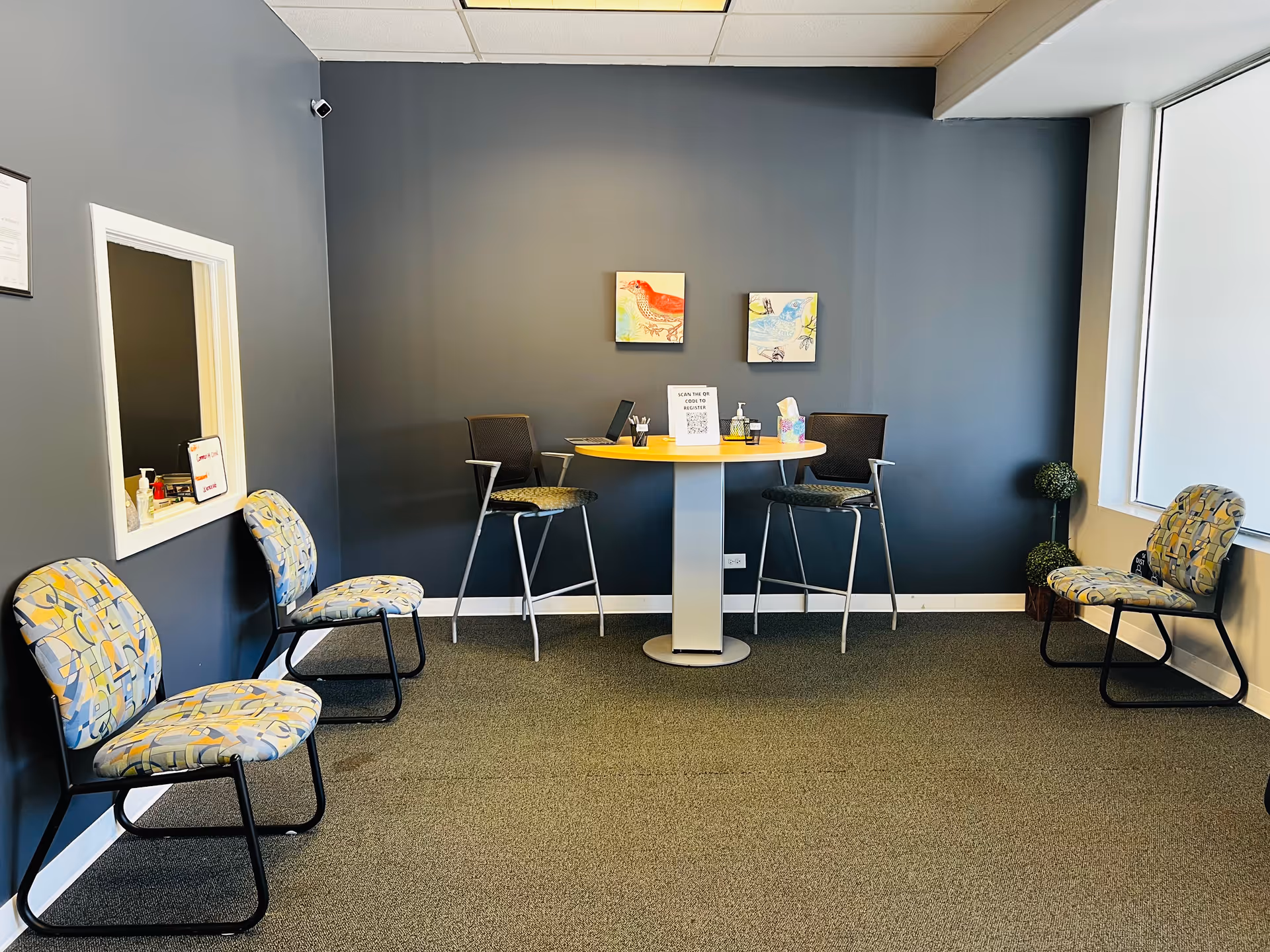 A small indoor lounge with a round table, high chairs, and blue walls.