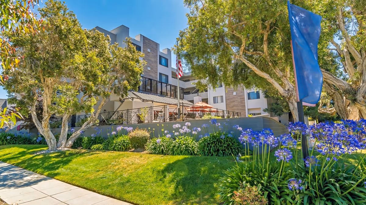 Exterior view of Burlingame Senior Living with landscaped gardens and a terrace.