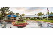 Exterior view of Aviara Healthcare Center with a circular garden bed and American flag.