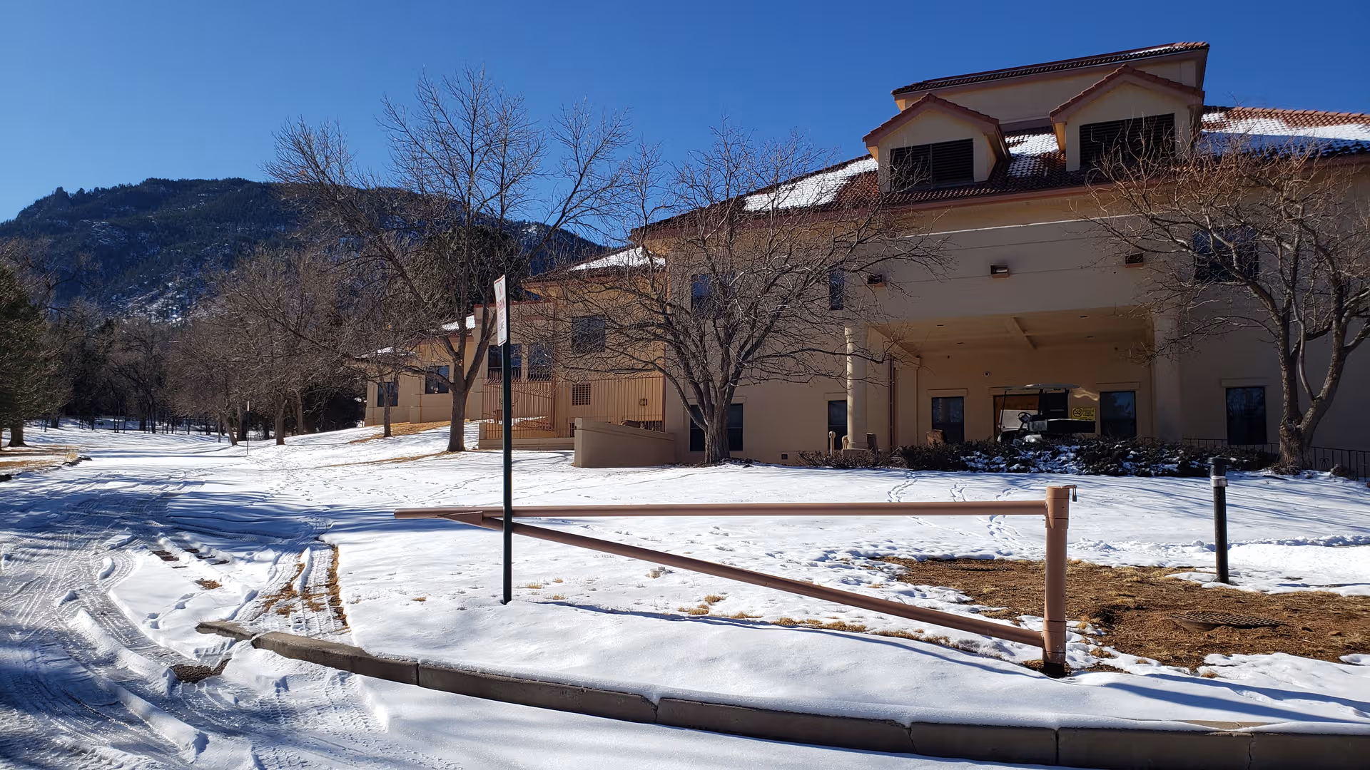 Snow covers the front of a Namaste Alzheimer Center building with bare trees.