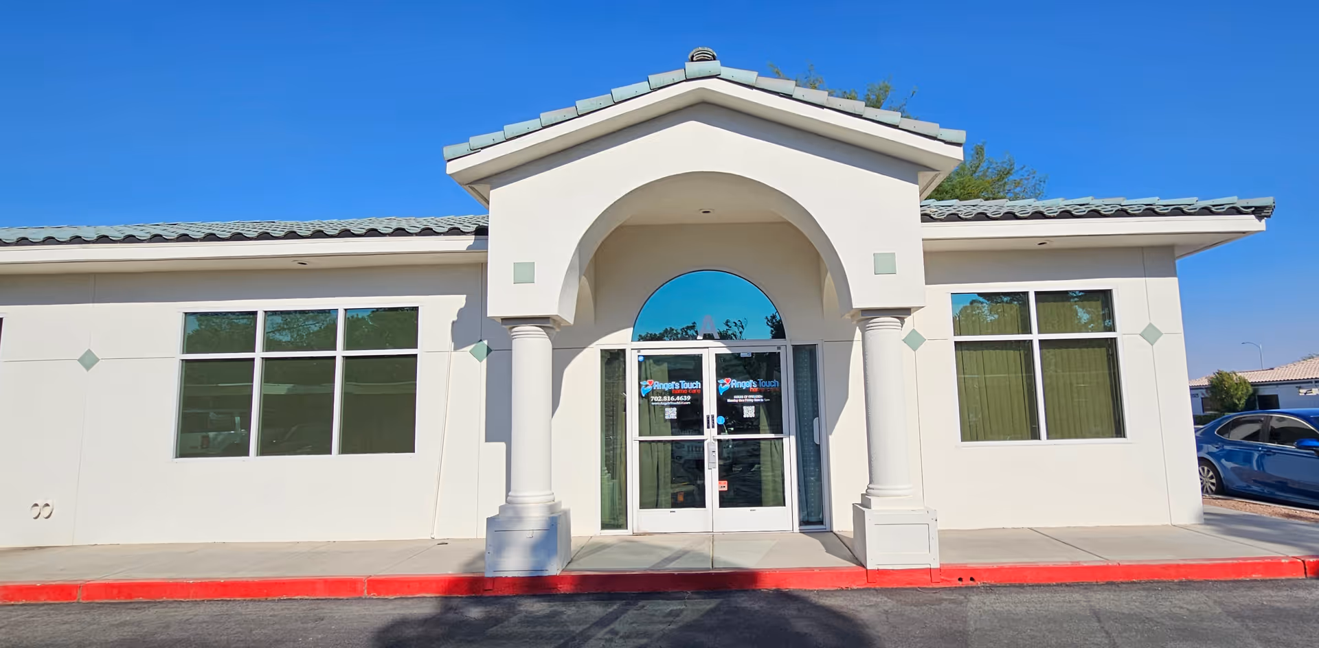 White, single-story building with arched entrance and glass doors labeled Angels Touch Home Care.