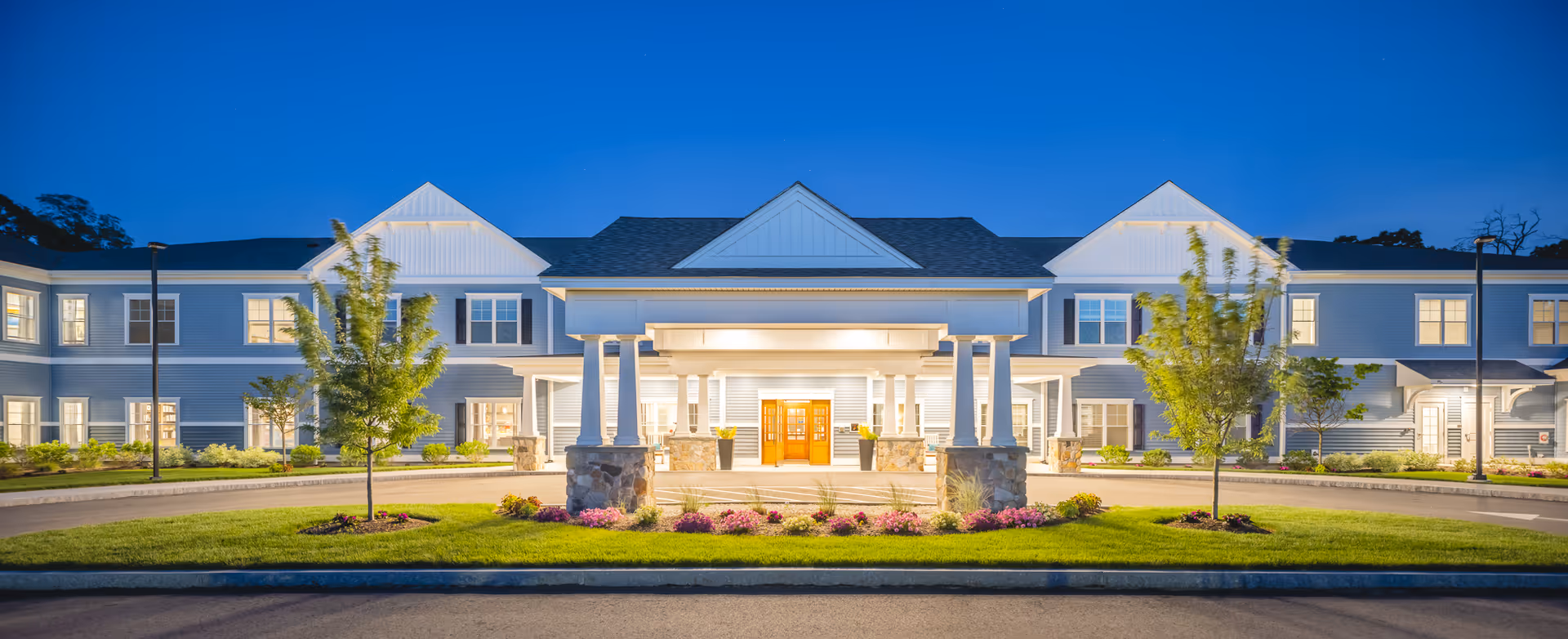 Exterior view of The Branches of Marlboro building entrance with illuminated porch at dusk.