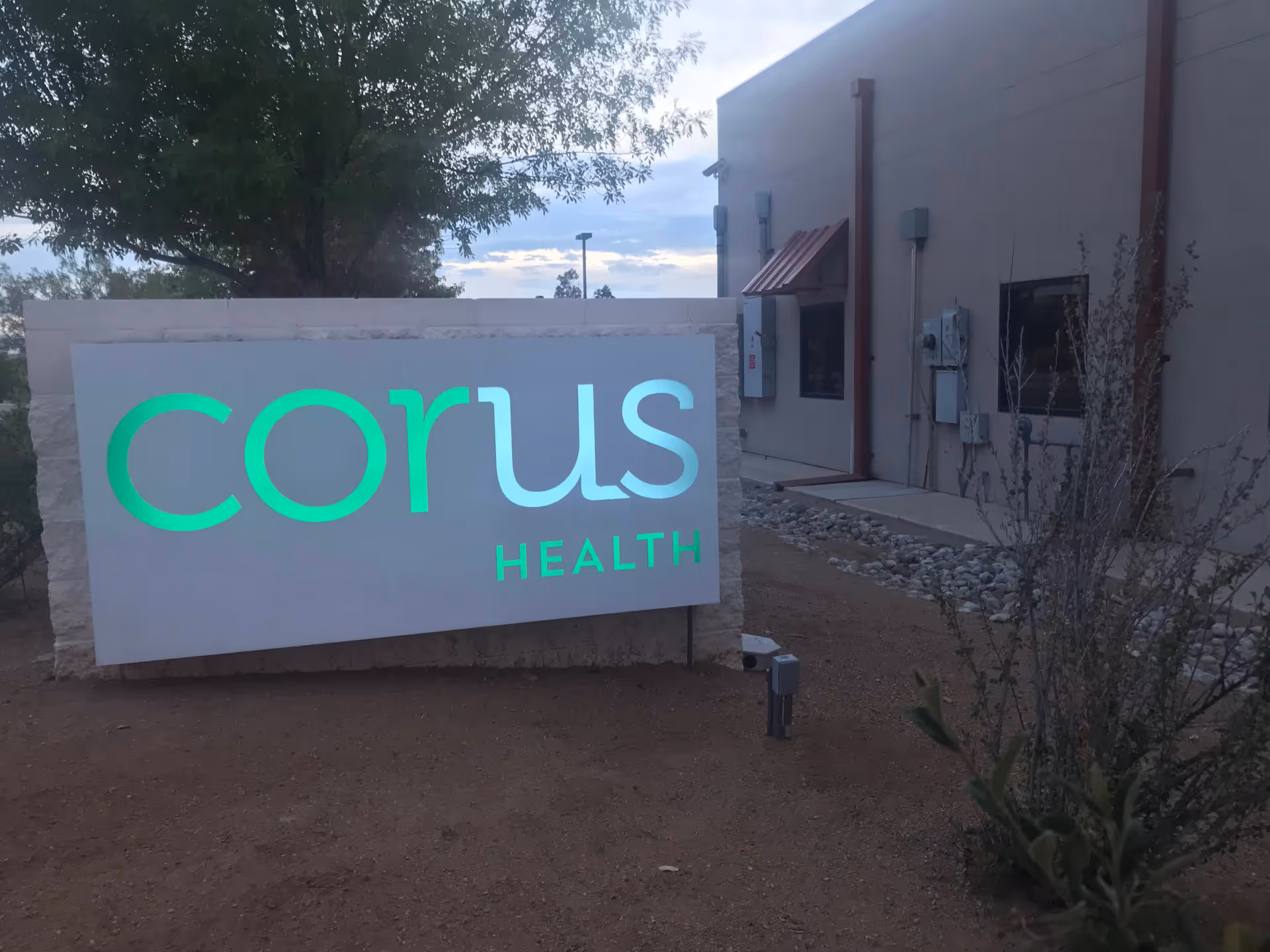 Exterior view of the Corus Health sign by the building entrance.