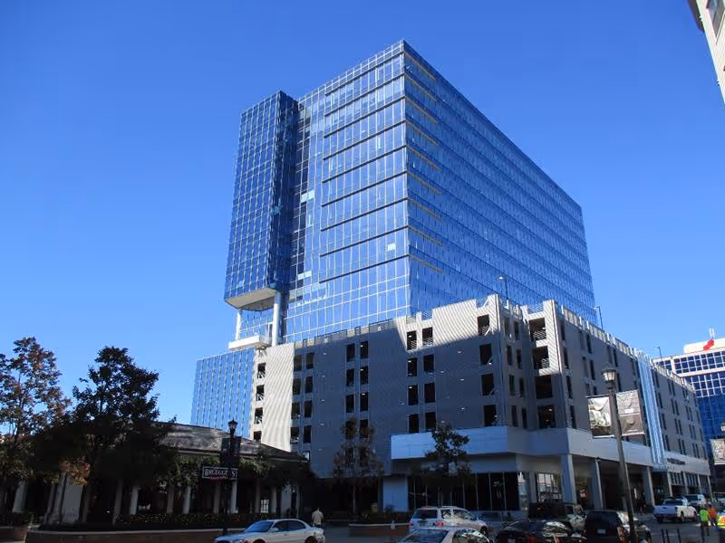 Tall modern glass office building against a clear blue sky.