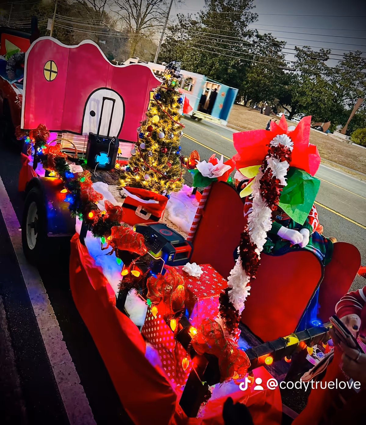 A colorful holiday parade float with a pink castle and Christmas tree on a trailer.