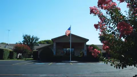 Front view of Granbury Care Center with flagpole and parking lot.