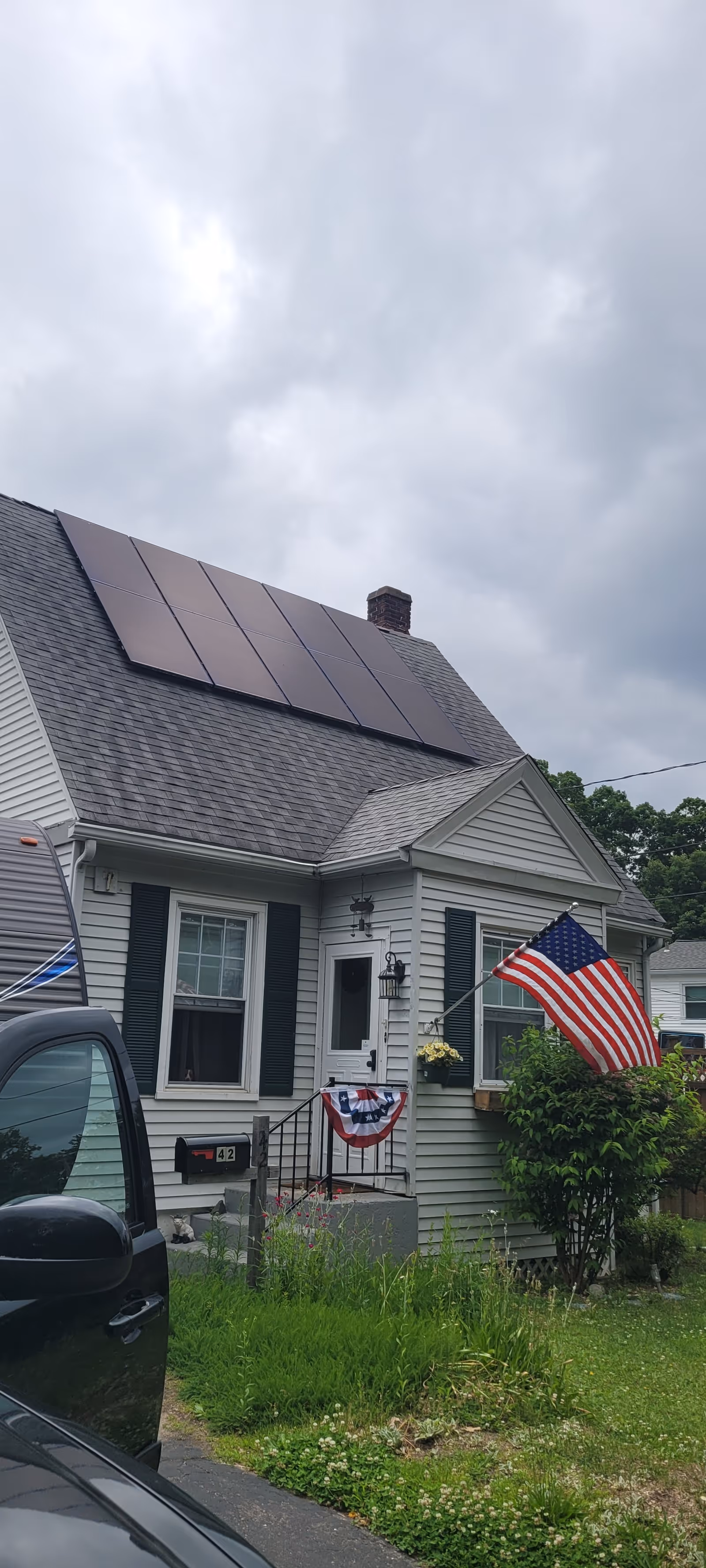 Front view of a house with solar panels, a US flag, and patriotic decorations.
