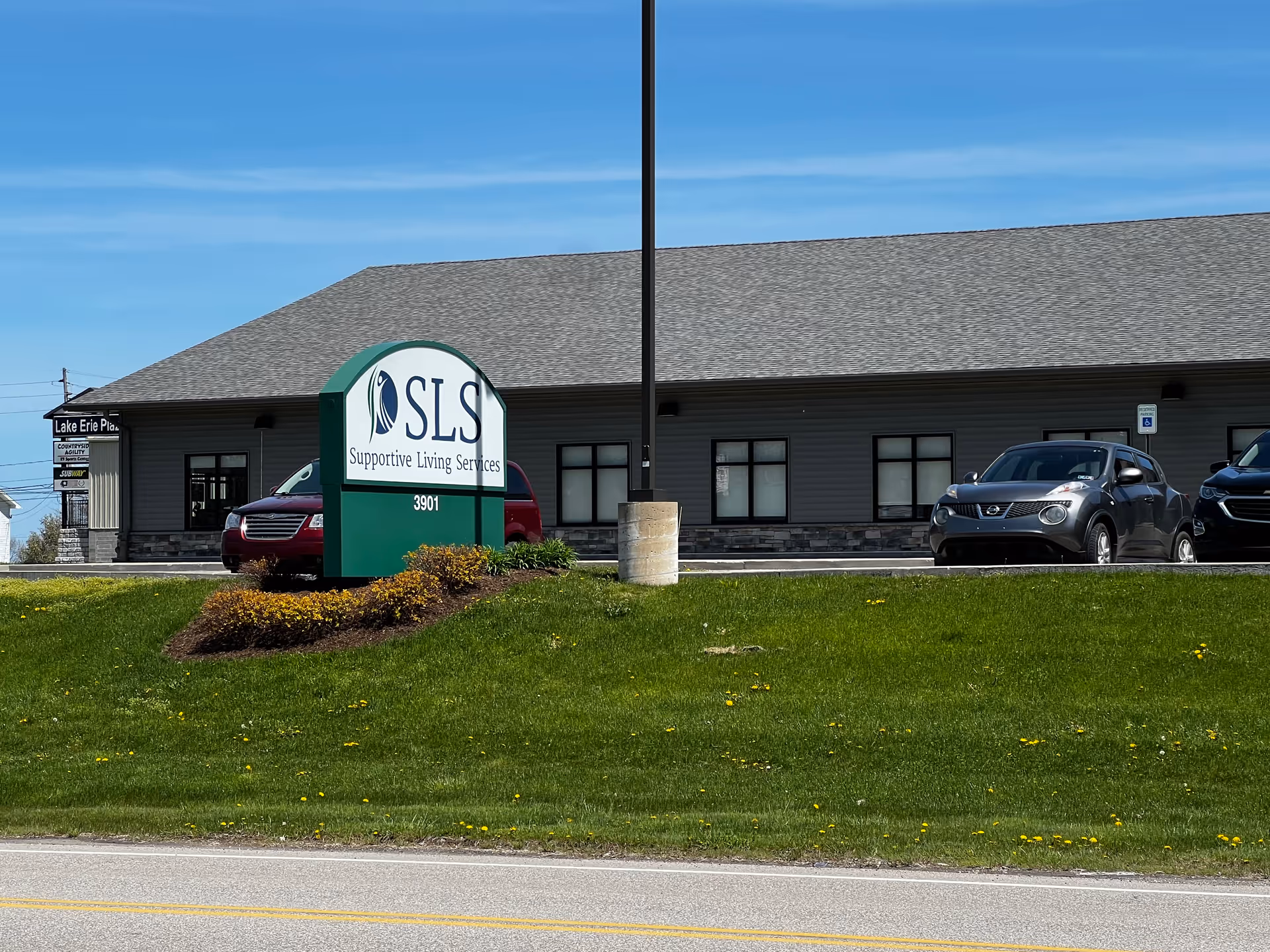 Exterior view of a Supportive Living Services facility with a large sign and cars.