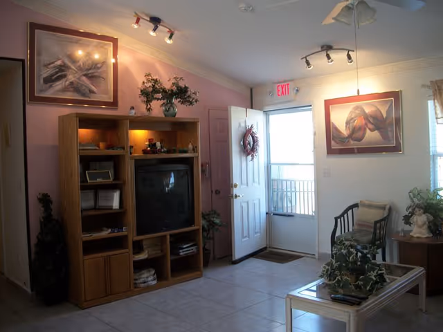 Cozy senior living room with TV cabinet, seating, and decorative artwork.