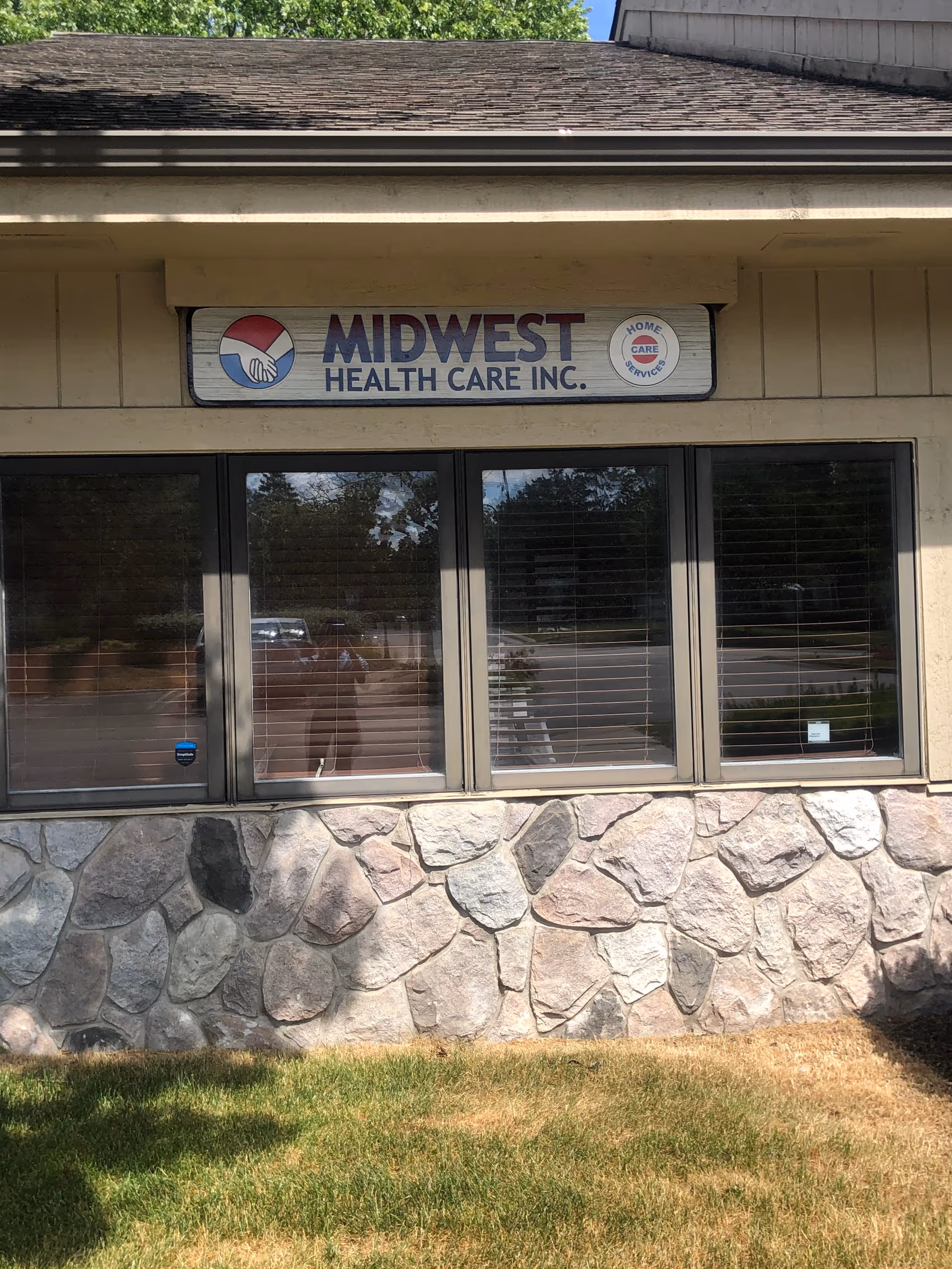 Exterior view of Midwest Health Care Inc. building entrance with stone façade and sign.