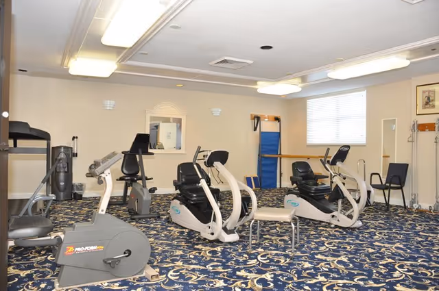 Interior fitness room at The Horizon Club with exercise bikes, treadmill, mirrors.