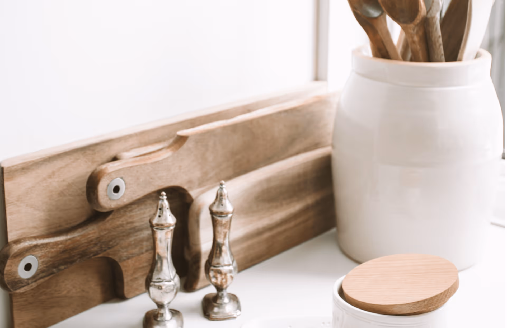 Close-up of a kitchen counter with wooden cutting boards, utensils, and jars.