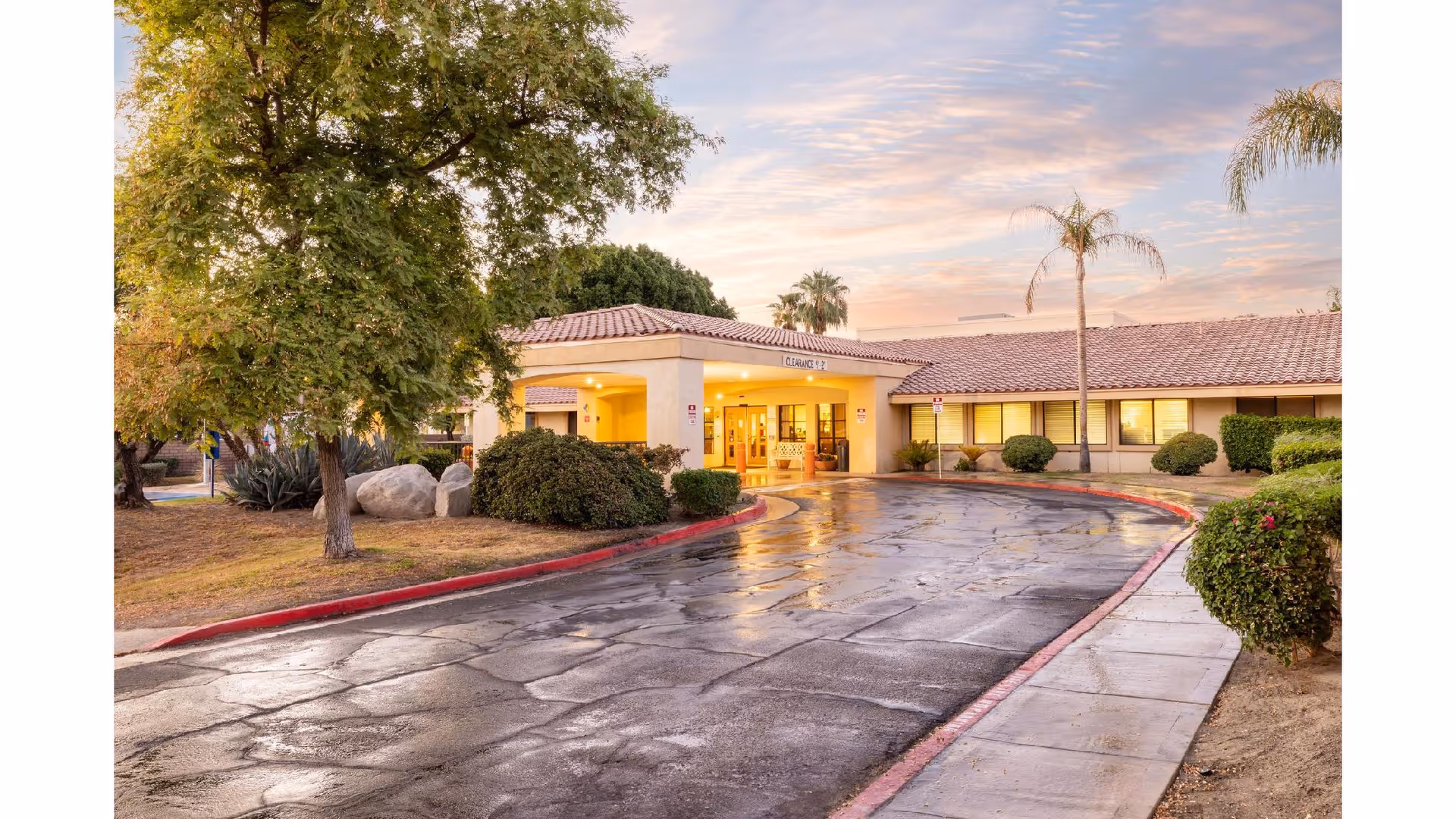 Exterior view of ManorCare Palm Desert entrance with curved driveway and landscaping.