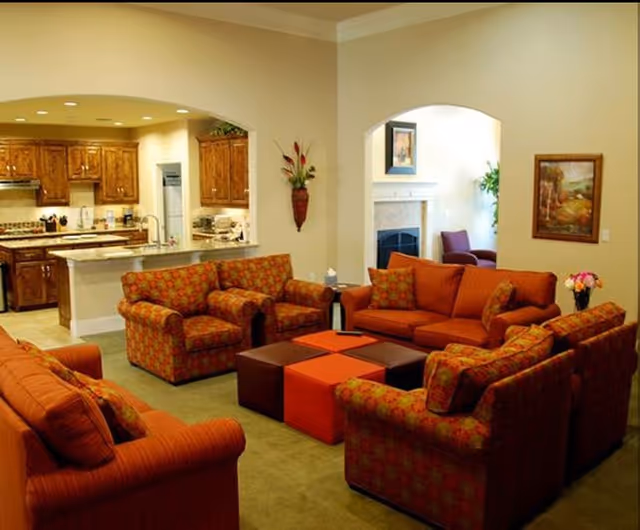 Cozy living room with orange upholstered seating and arched kitchen openings.