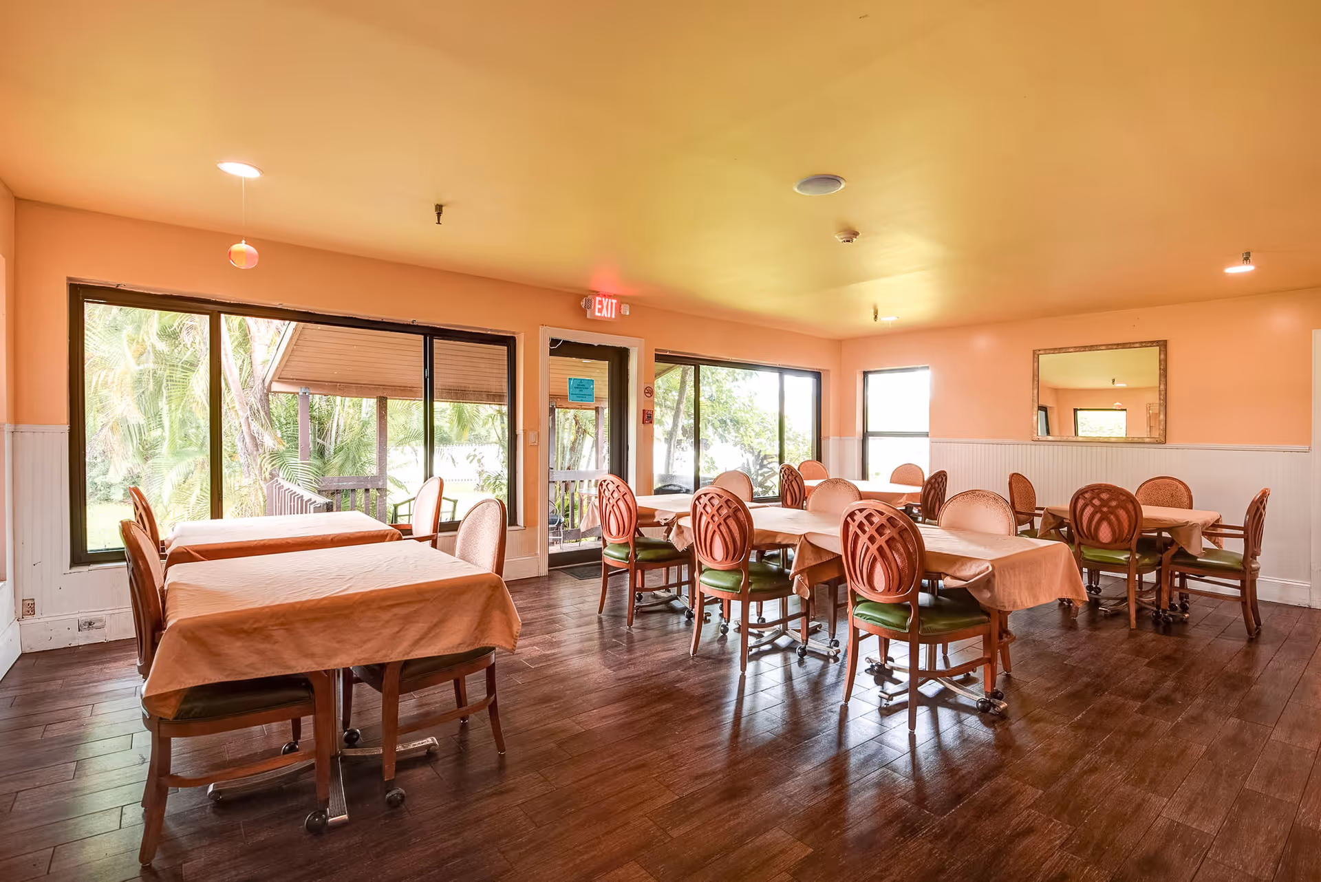 Bright dining room with multiple tables, peach walls, and large windows.