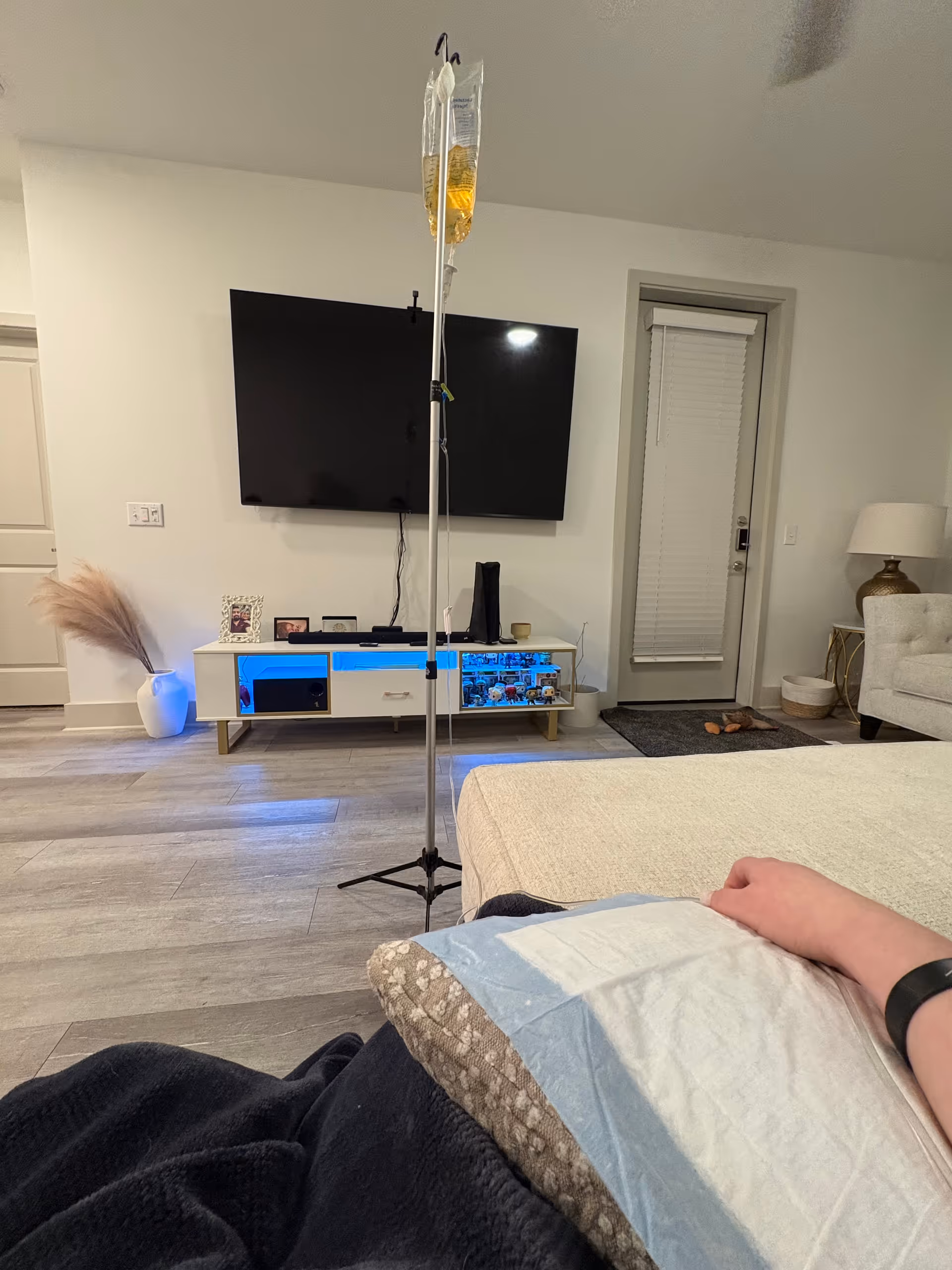 IV drip bag on stand beside a bed in a modern bedroom.