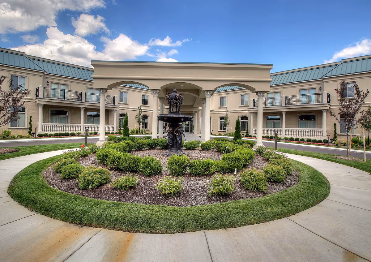 Exterior view of Tranquility Estates featuring a circular driveway, fountain, and greenery.