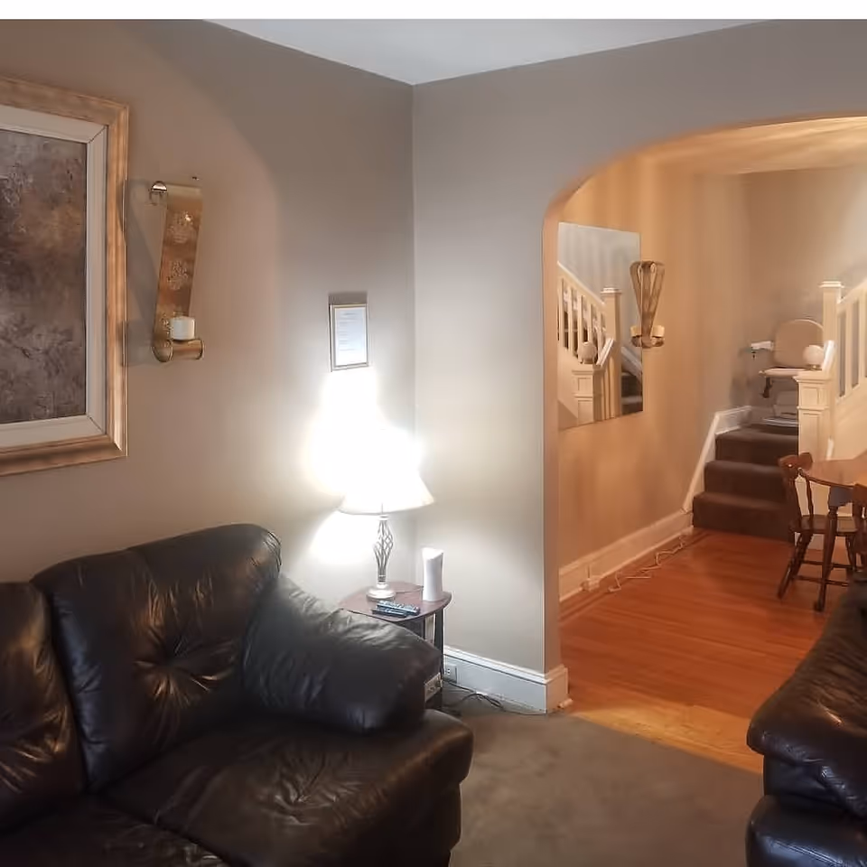 Cozy living room with leather sofas, a lamp, framed art, and archway.