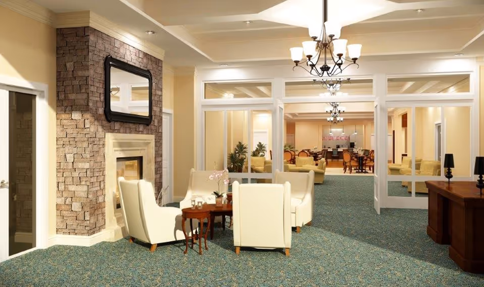Senior living facility living room with a stone fireplace, cream chairs, glass partitions, and chandeliers.