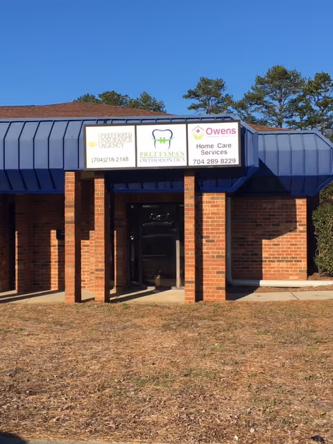 Brick building entrance with a blue awning and Owens Therapeutic Services signs.