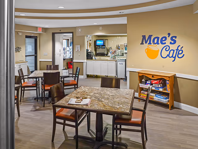 Interior dining area with tables, chairs, and a Mae's Café sign on the wall.