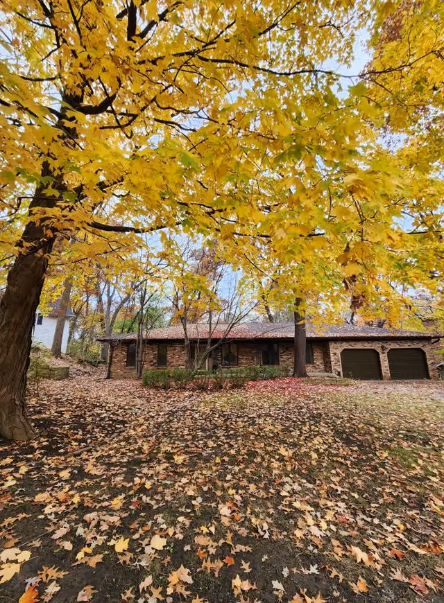 Autumn exterior view of Wildwood Elder Estate with brick facade, trees, and fallen leaves.