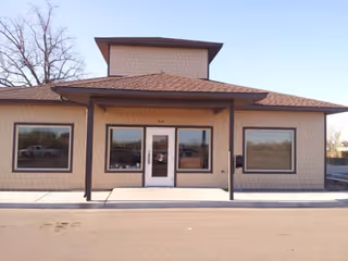 Outside view of an Enhabit Hospice single-story building with glass doors and windows.