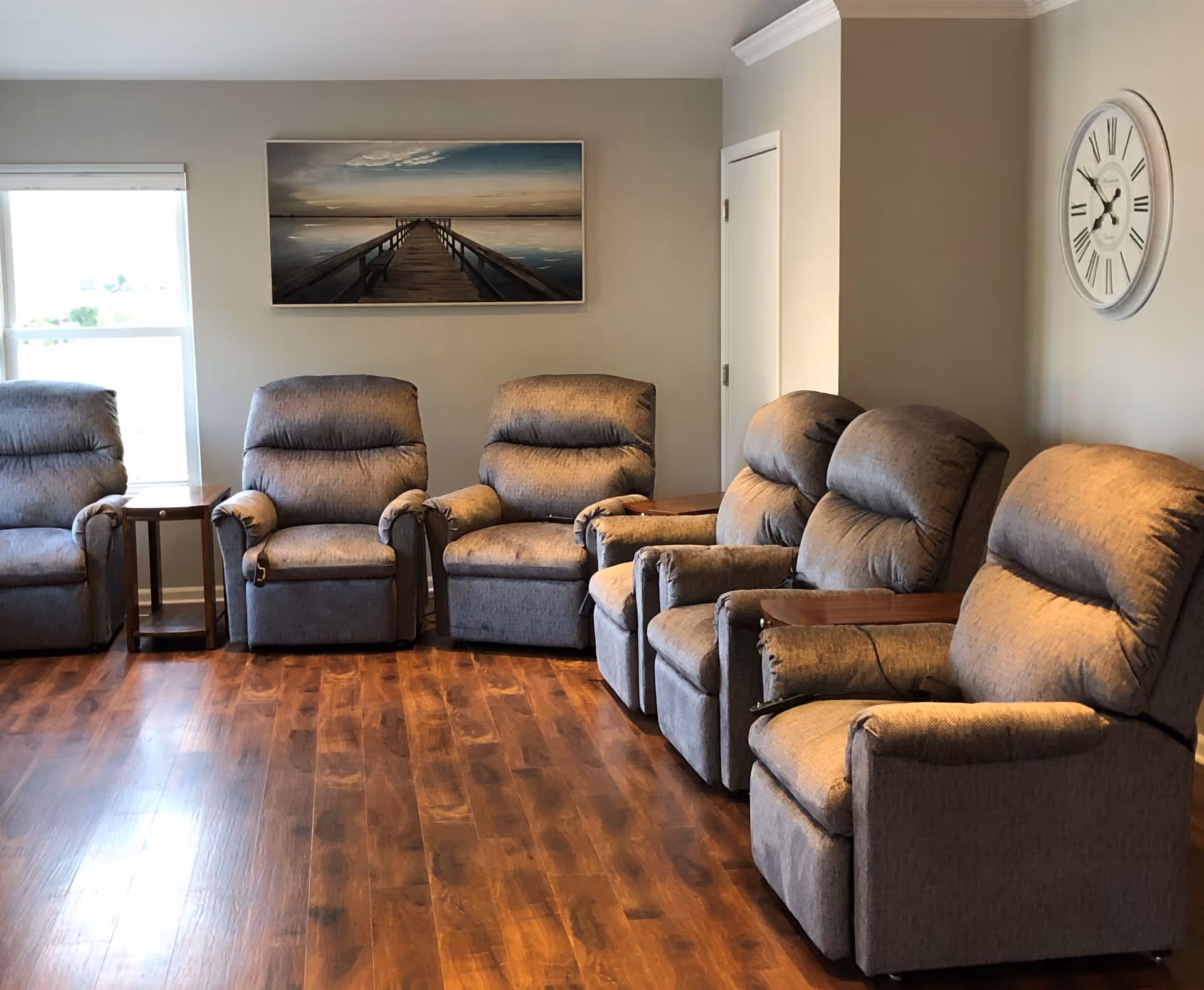 Row of cushioned recliners arranged in a cozy living room with wood flooring.