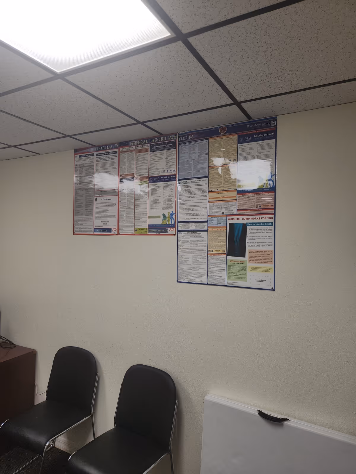 Interior room with three black chairs and wall-mounted informational posters.