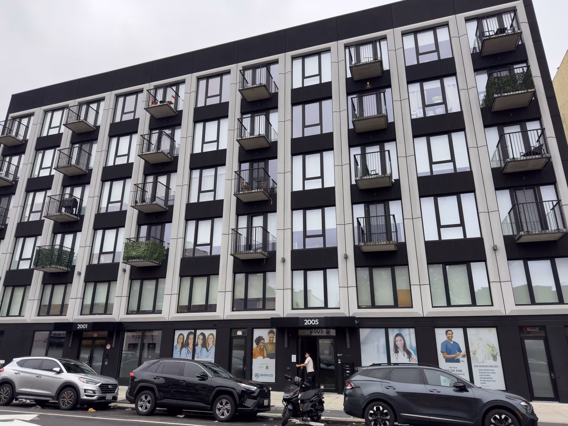Exterior view of a modern multi-story building with balconies and storefronts.
