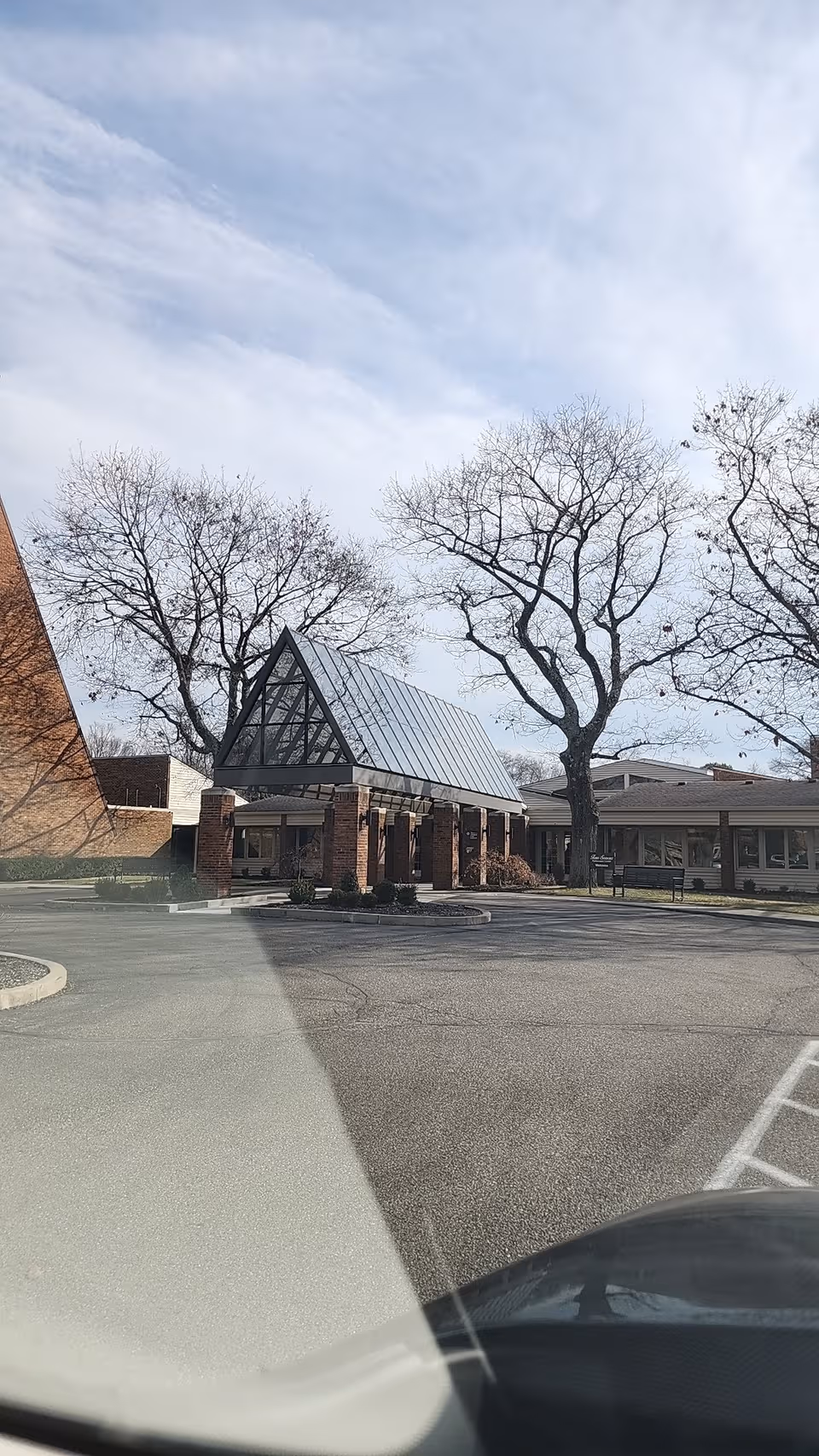 Front view of a retirement center entrance with brick columns and glass roof.