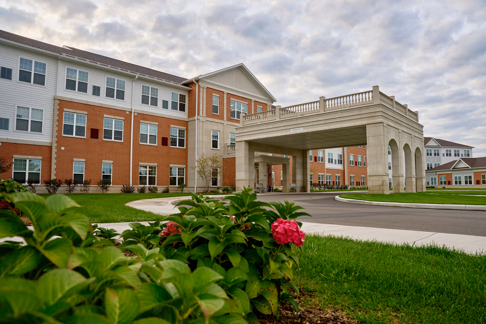 Exterior view of Harmony at Elkhart with brick facade and porte-cochère entrance.